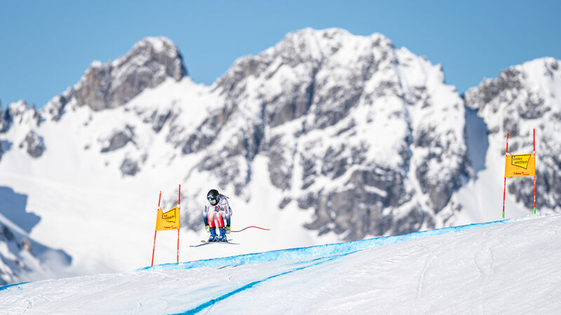 Skifahrerin springt am Kandahar Rennen in St. Anton am Arlberg. Dahinter eine traumhafte Bergkulisse im verschneiten Winter.
